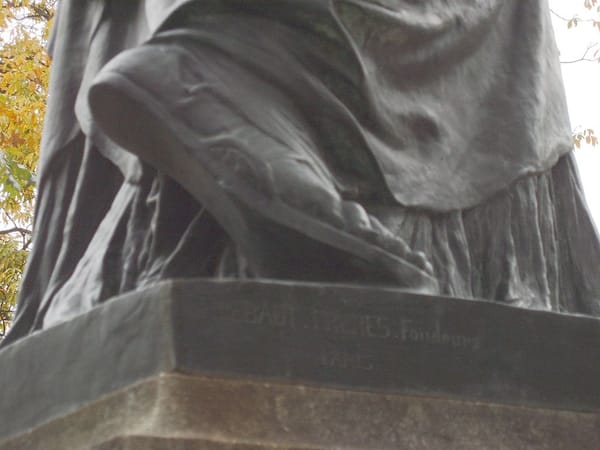 Image of the Statue of Liberty, zoomed in on her right sandaled foot, heel upraised from the pedestal.